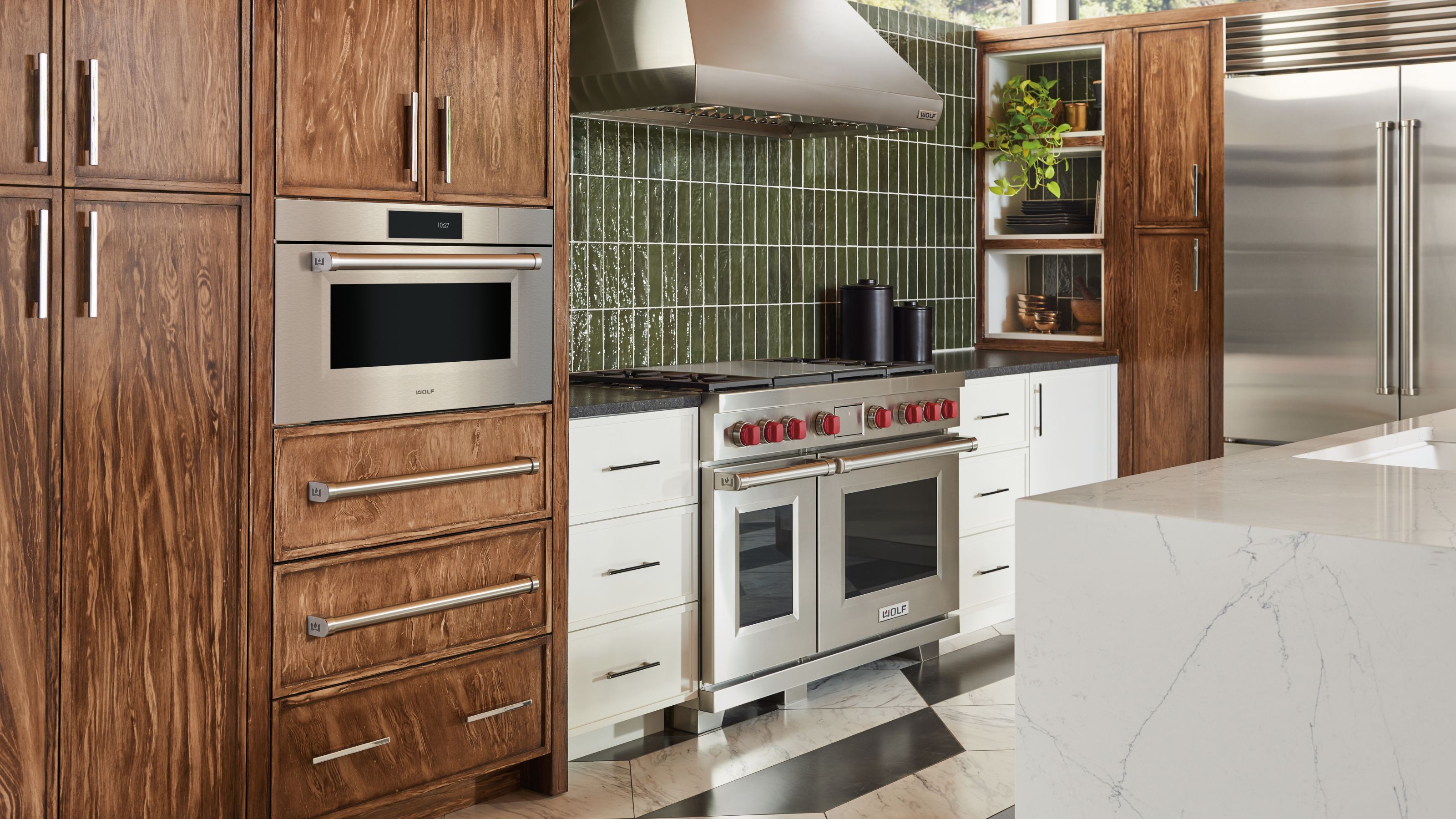 A kitchen with wooden cabinets and a proving drawer on one side as well as a view of the oven and stove 