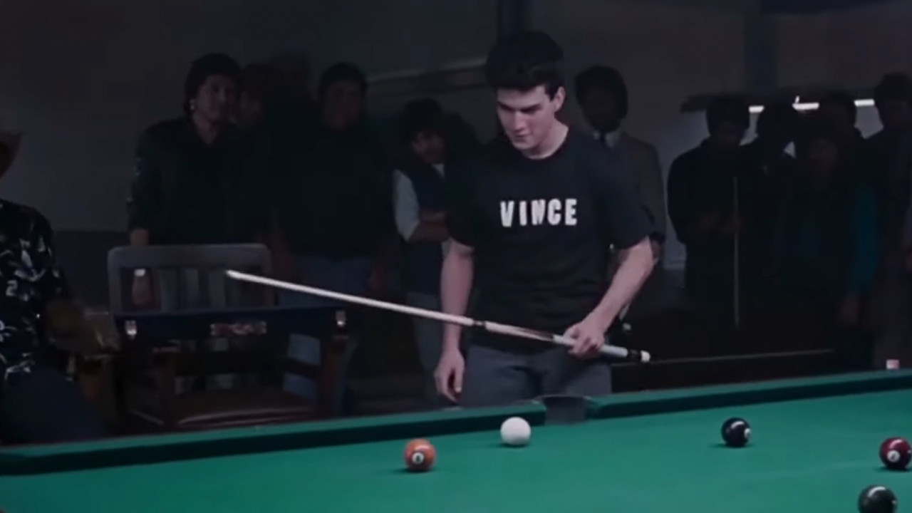 Tom Cruise playing pool, with a black t-shirt that says 