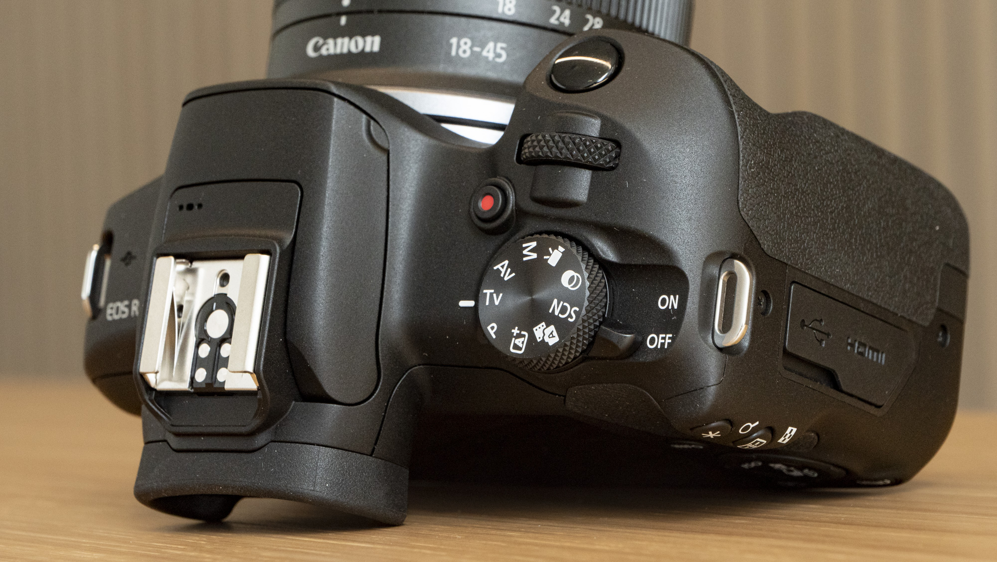 Canon EOS R100 camera on a table closeup of shooting mode dial