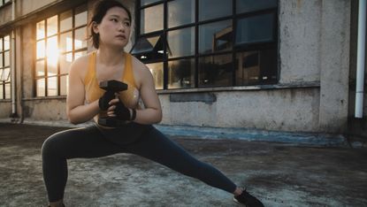Woman doing a cossack squat with a dumbbell