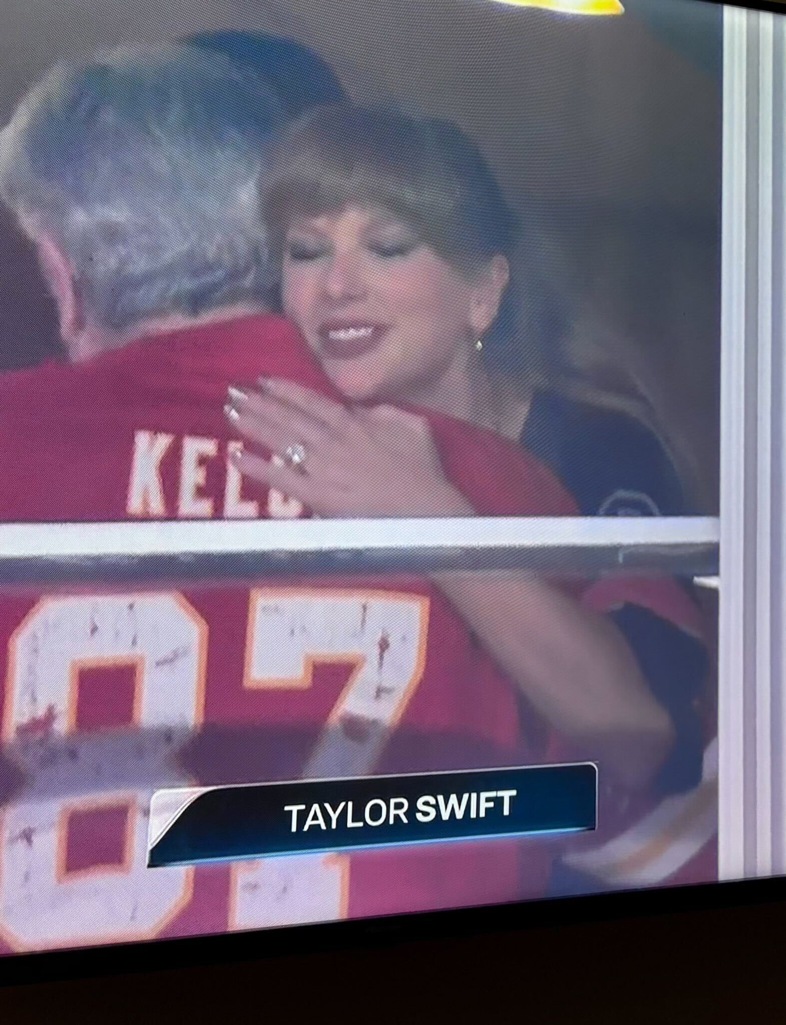 Taylor Swift attending the Kansas City Chiefs Detroit Lions game wearing a black jersey with her engagement ring