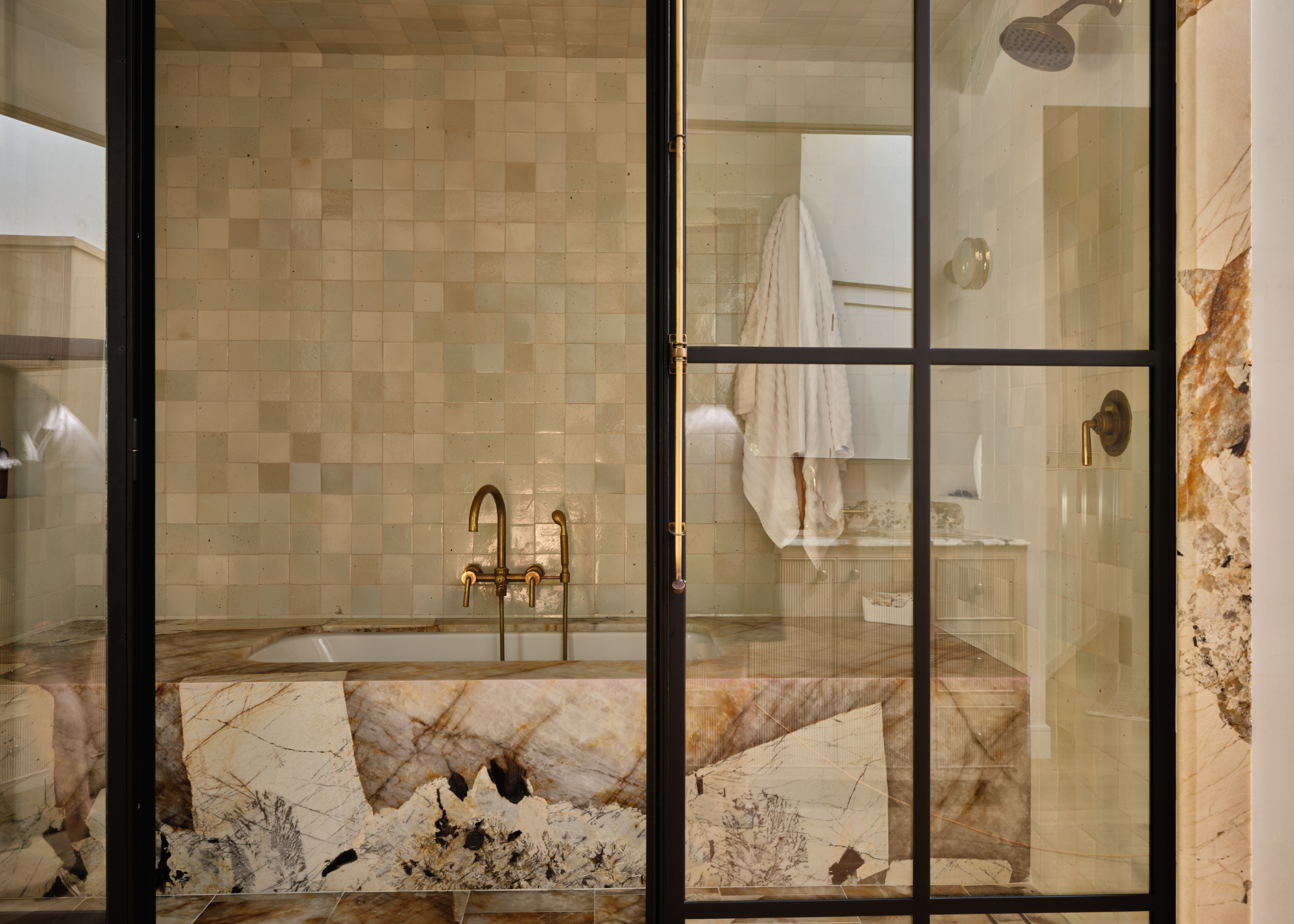 beautiful marble bath with zellige tiles behind in a shower enclosure of crittal doors