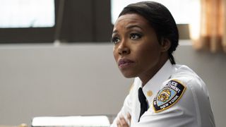 Amanda Warren as Regina Haywood sitting in uniform in East New York