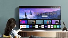 A woman sat in front of an LG C3 OLED TV in a blue living room