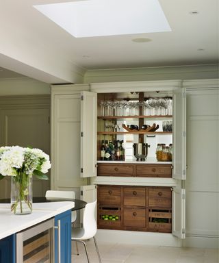 large floor-to-ceiling kitchen cabinets with top section used as bar, storage drawers below