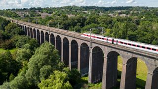 great british rail sale - train crossing a bridge in the countryside - 1558395375