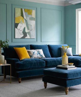 Blue painted living room with painted moulding details on wall and blue velvet sofa