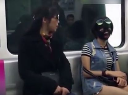 woman wearing sheet mask on train