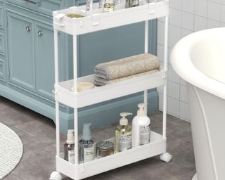 a white utility cart next to a white tub and a blue vanity in a tight space