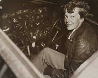 Amelia Earhart photographed sitting in the cockpit of the Lockheed Electra airplane around 1936.