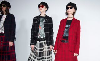 Models wear red and black patterned suits and skirts with with printed t-shirts, ivy caps and sunglasses