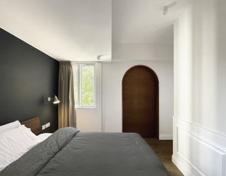 A bedroom with a dark painted alcove