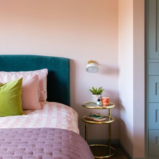 a pink bedroom with velvet double bed and gold side table