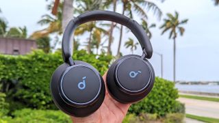 Anker Soundcore Space Q45 headphones placed in reviewer's hand with outdoors Florida scene in background