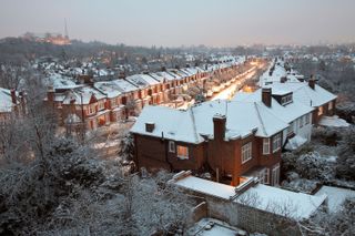 A UK street with snow on the roofs of the houses