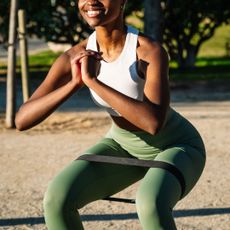 A woman doing a YouTube resistance band workout in the park