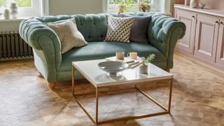 wooden Amtico flooring in living room with green sofa and white and gold framed coffee table