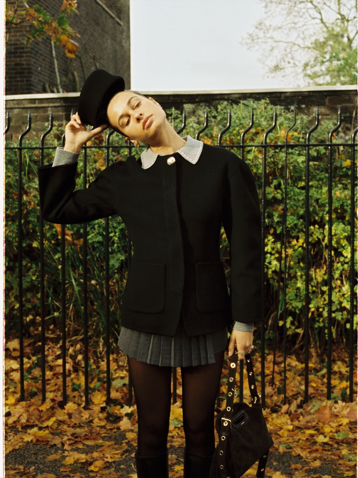 Fashion person Sarah Lysander wears winter knitwear trends 2025. She wears a black waited cardigan with a grey mini skirt. This image was taken from her Instagram.