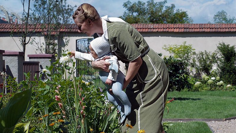 movie still showing a woman holding a baby in a garden