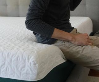 Camryn's husband sitting on the side of the Zinus Cooling Green Tea Mattress.