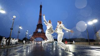 Egyptian athletes in white dance in front of Eiffel tower at night at the 2024 Olympic Opening Ceremony.