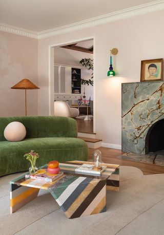 σαλόνι με πράσινο κυρτό καναπέ ροζ τοίχους και ριγέ τραπεζάκι