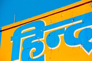 Photo of blue and white writing against a yellow background under a blue sky