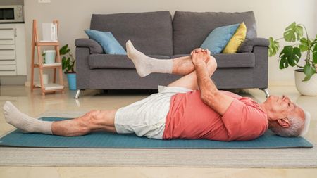 a senior man lying on an exercise mat 