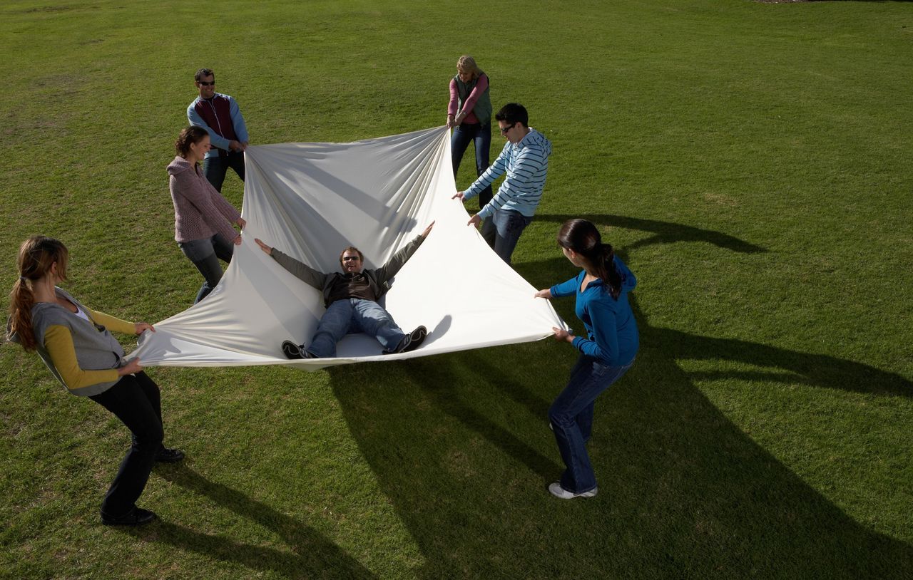 A group of people catch a person in a safety net.