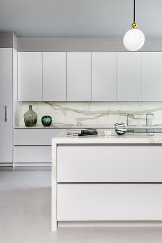 white and marble modern kitchen, white floor, green vases, white globe pendant