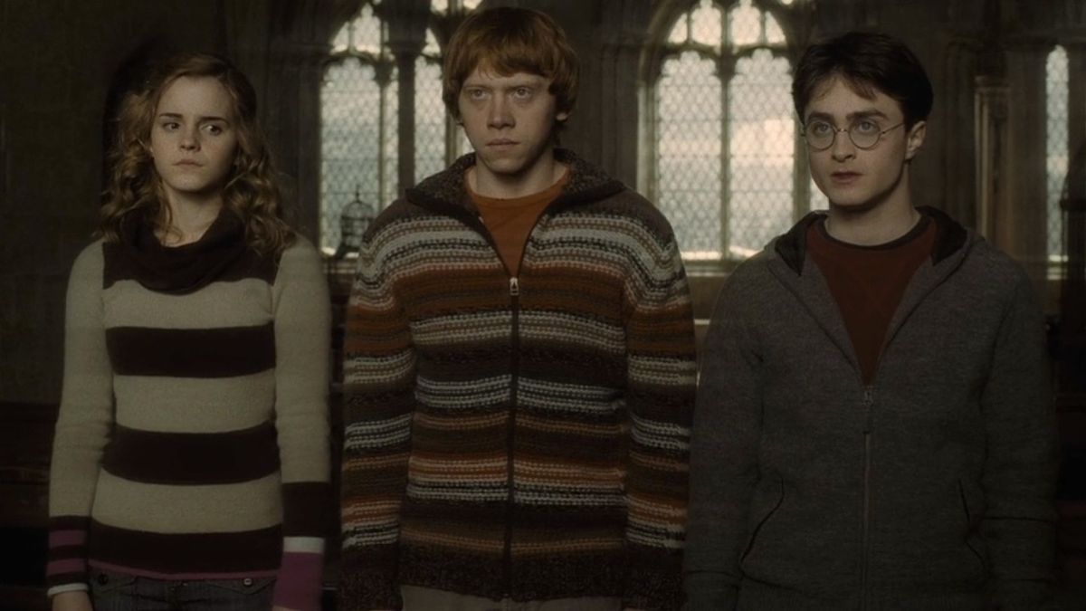 From left to right: Hermione, Ron and Harry all standing next to each other looking like they just got in trouble.