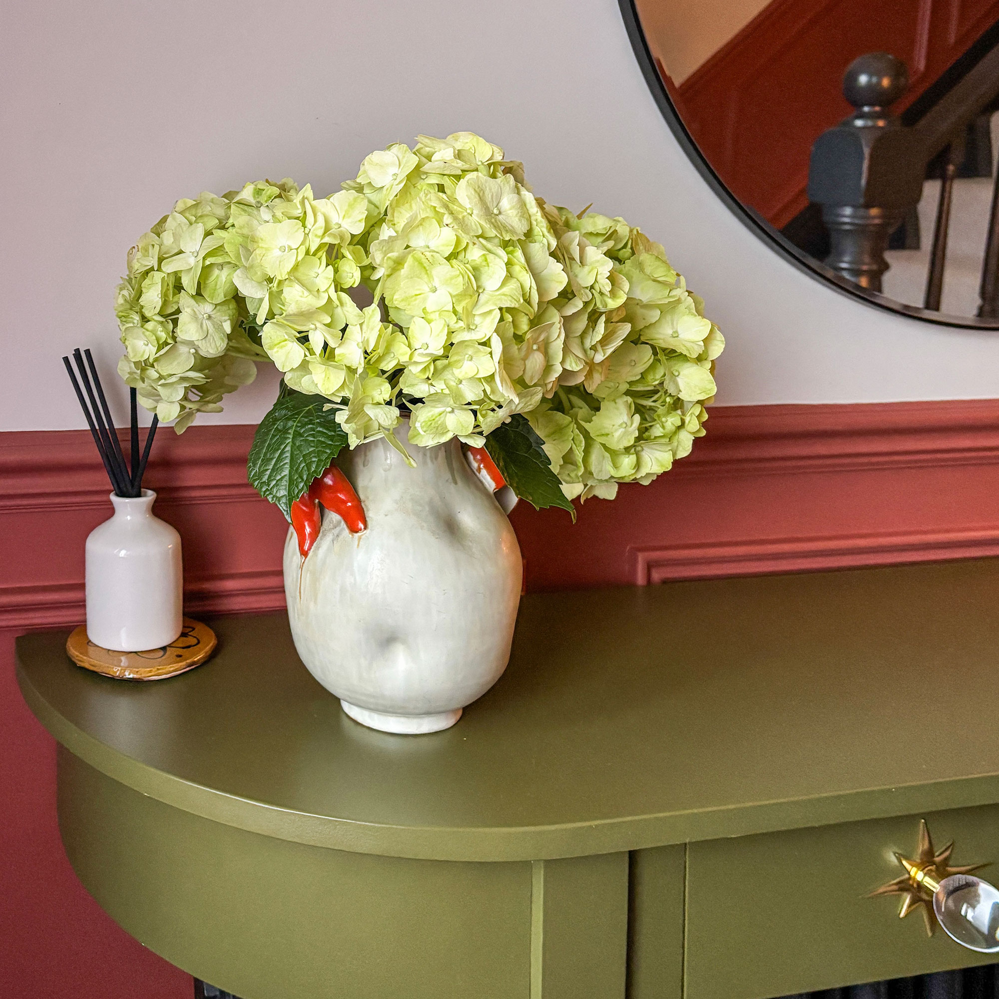 Vase of hydrangeas on green radiator cover shelf