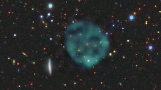 The ghostly ORC1 (blue/green fuzz), on a backdrop of the galaxies at optical wavelengths. There’s an orange galaxy at the centre of the ORC, but we don’t know whether it’s part of the ORC, or just a chance coincidence.