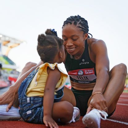 Allyson Felix sits on the track with her baby daughter