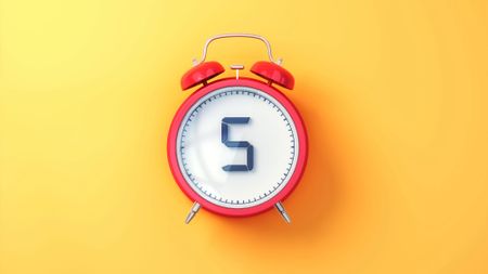 Red Alarm Clock with White Inside and Black Digit 5 on Yellow Soft Background 