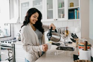 clean a kettle: woman pouring hot water