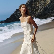 Woman wears white dress on beach 