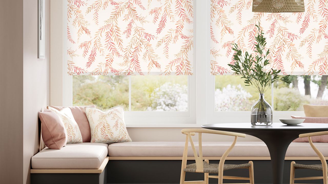 Blinds in orange leaf pattern over pink banquette seating