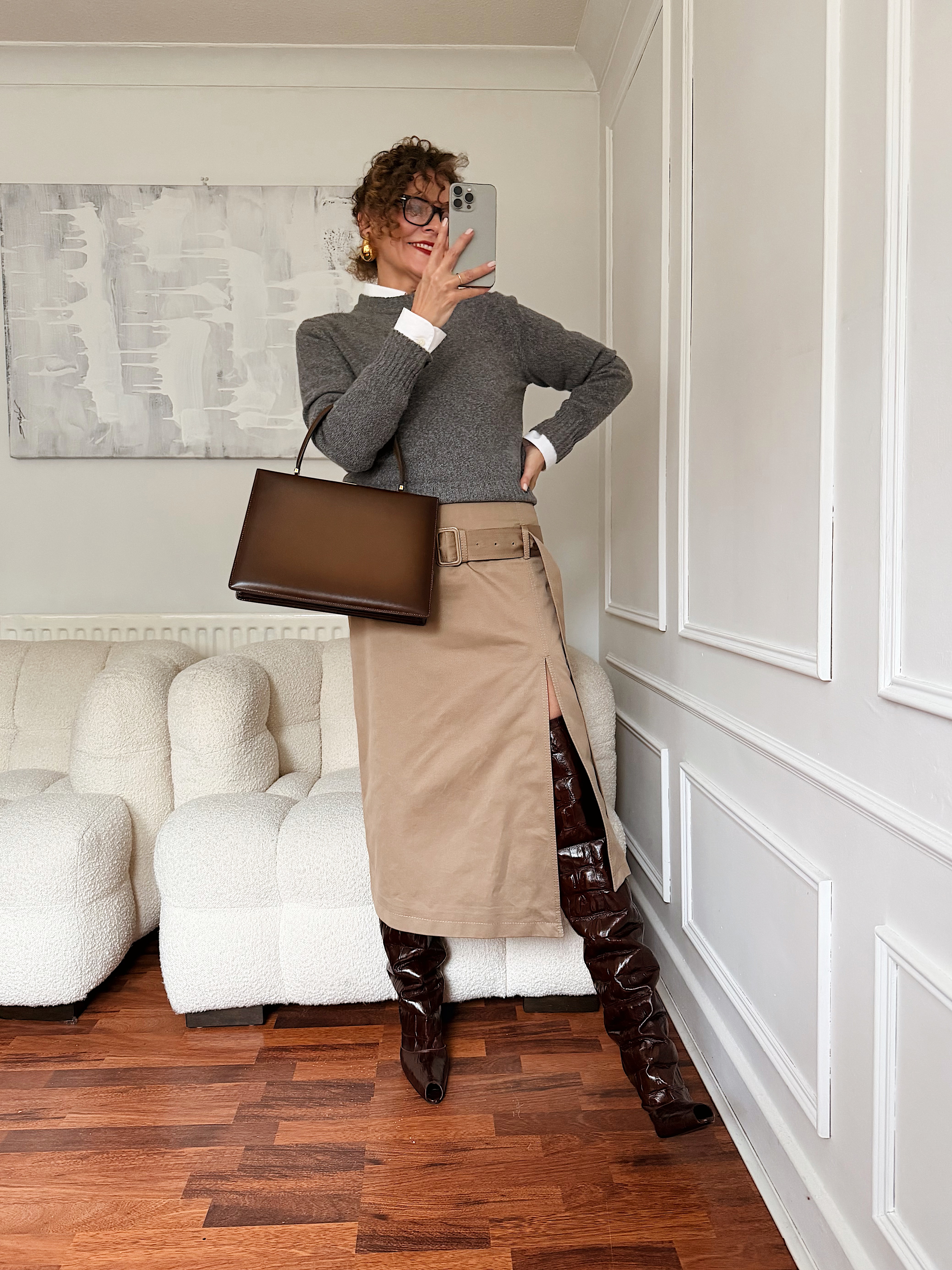 Renia Jazdzyk wearing a work outfit for mature women&amp;mdash;a grey sweater, belted midi skirt, and boots.