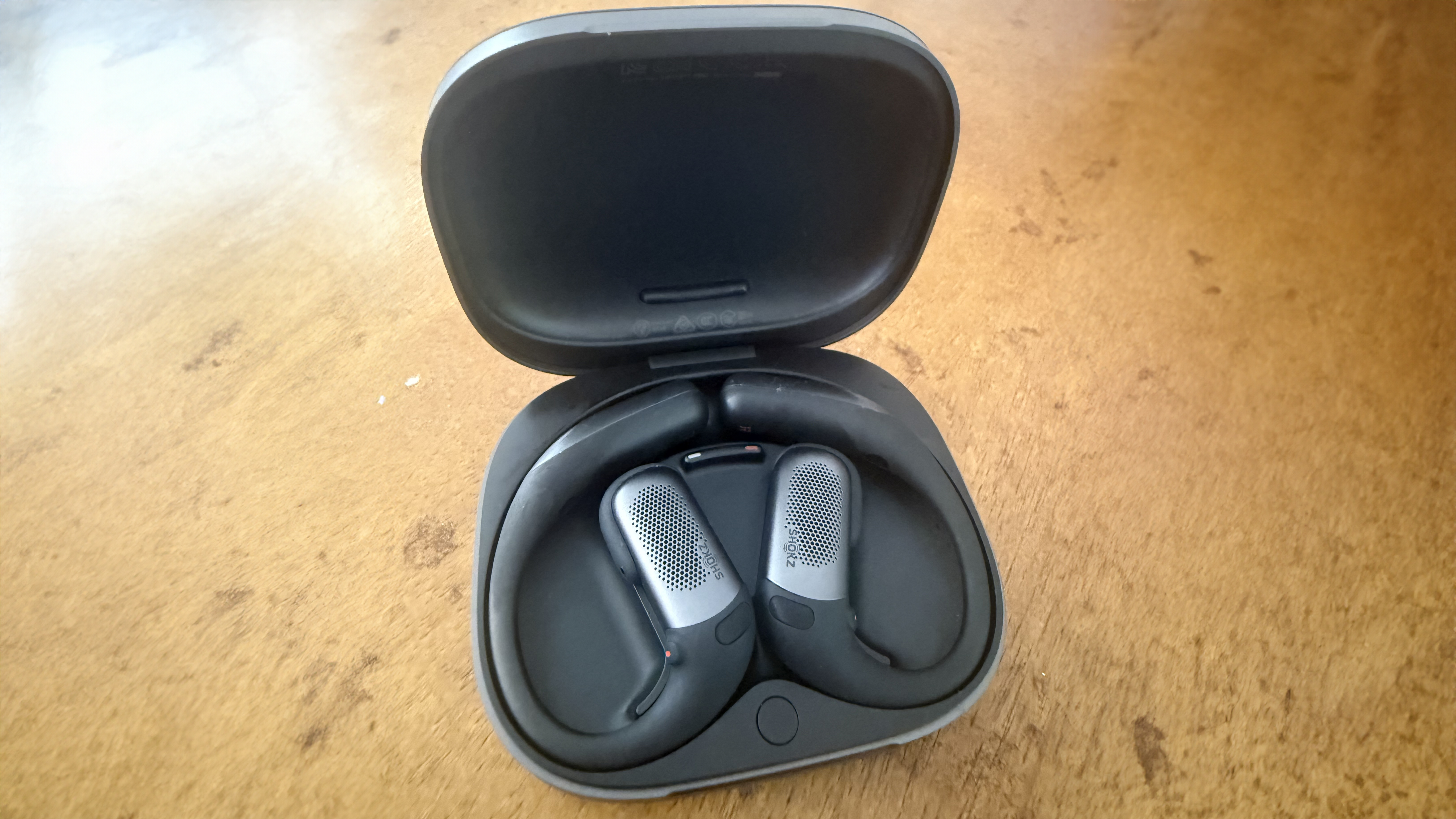The Shokz OpenFit Pro docked in its charging case