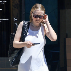 Actress Dakota Fanning steps out in a chic white maxi dress after getting her hair done at the salon in Los Angeles. She pairs the look with a black leather woven tote, black slippers, and stylish sunglasses.