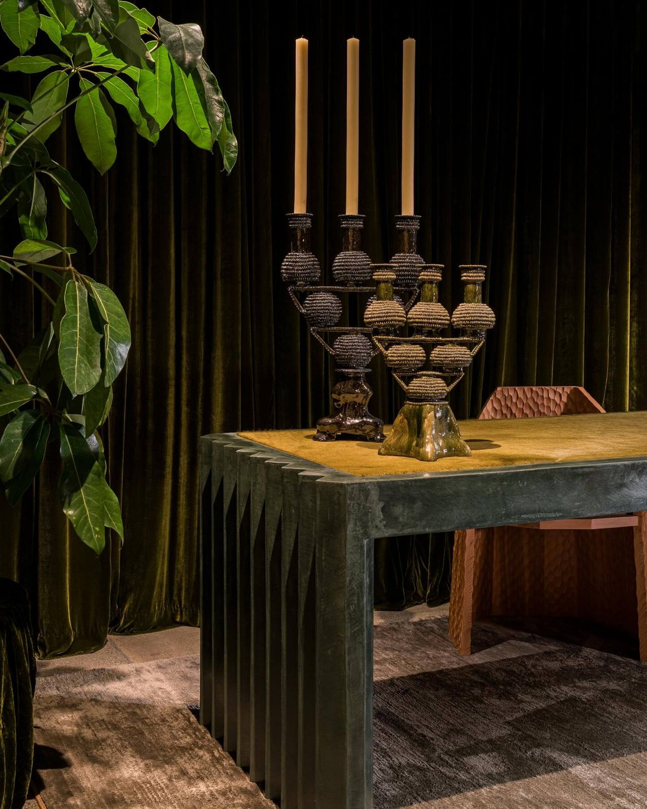 room with velvet green draped walls and a green desk with candelabras