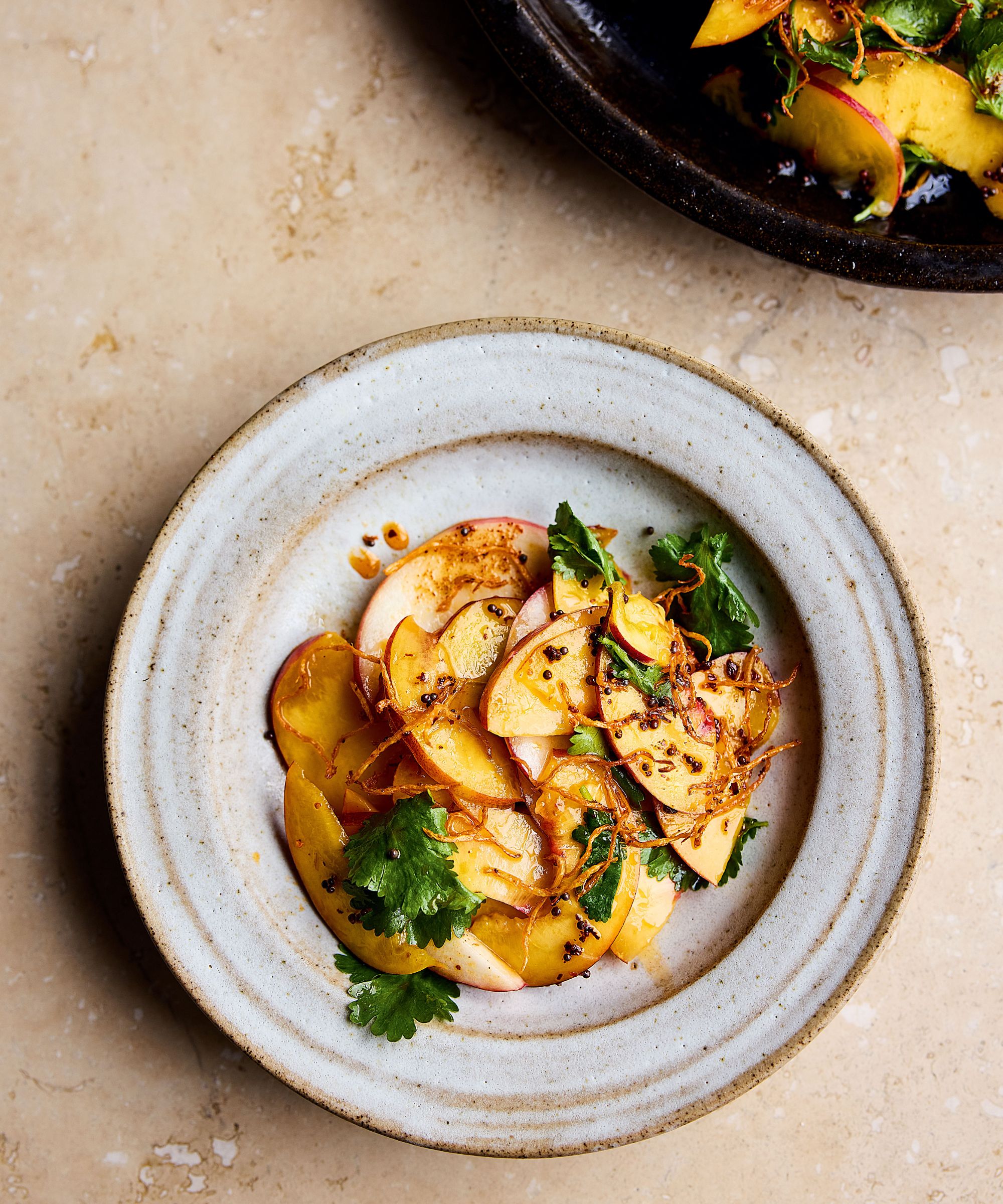 Plate of sliced nectarines with ginger and chilli dressing and coriander