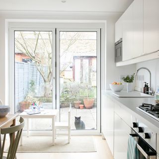 White kitchen-diner with floor-to-ceiling doors to garden