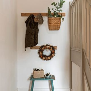 white wall with wooden hanger and plant sweater on it