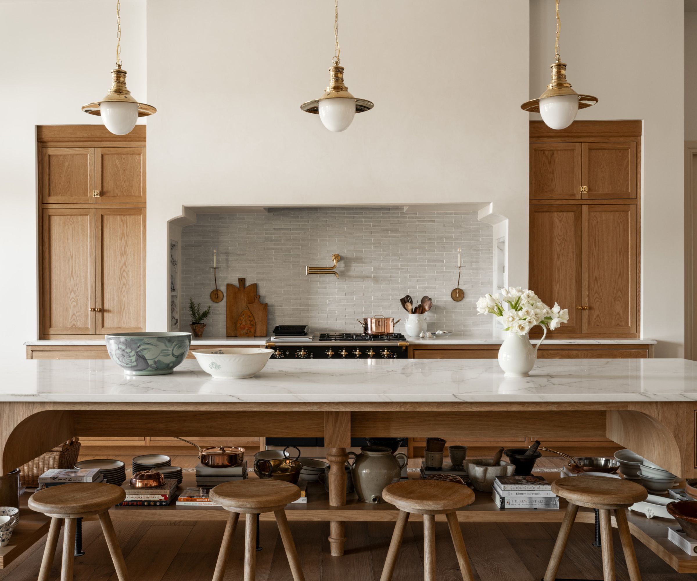 A large kitchen with wood cabinets, marble countertops, and brass accents