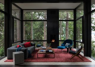 an architectural living room with a dark gray sofa, red rug and blue accent chair