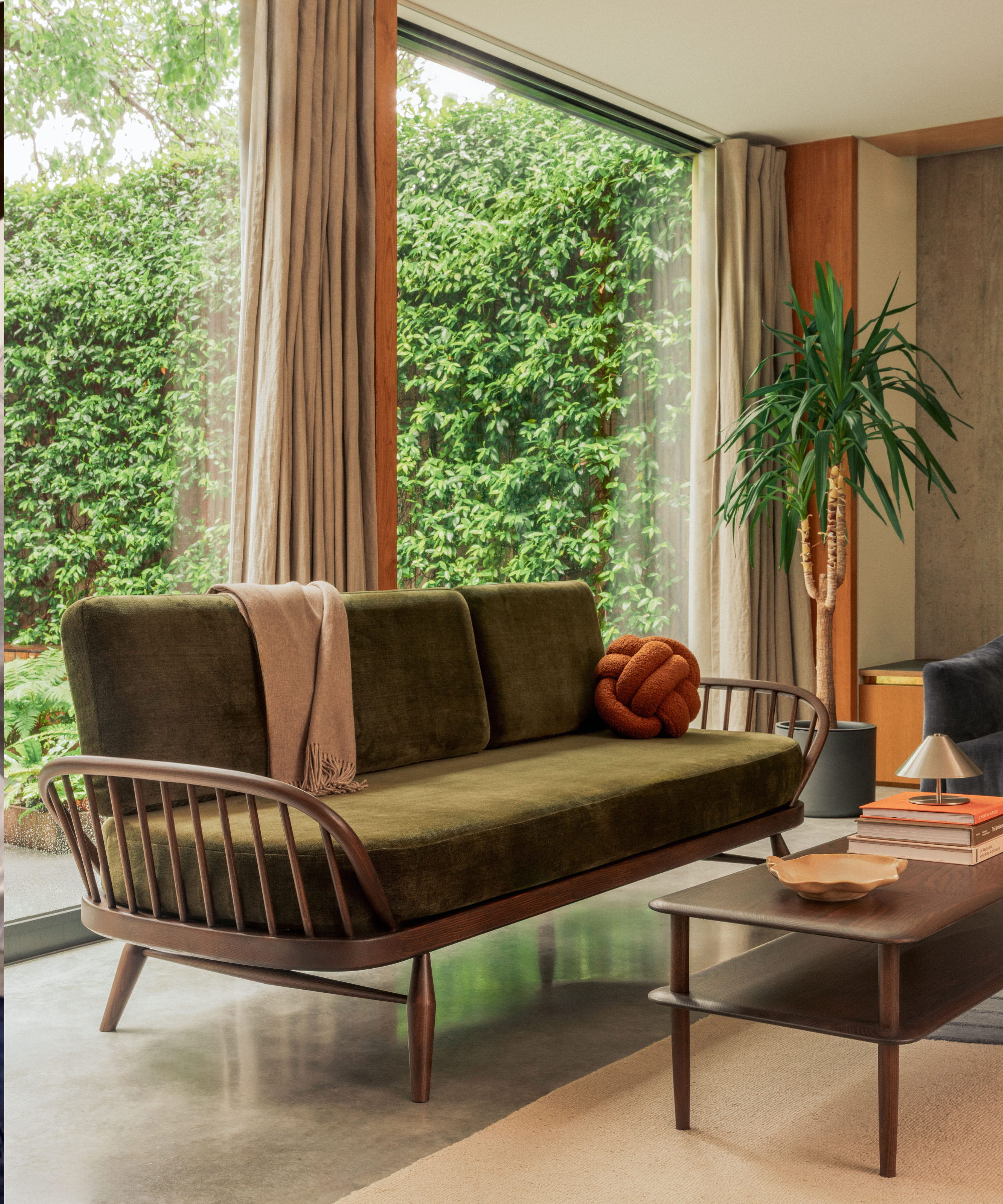 Mid century green sofa in living room with floor to ceiling windows
