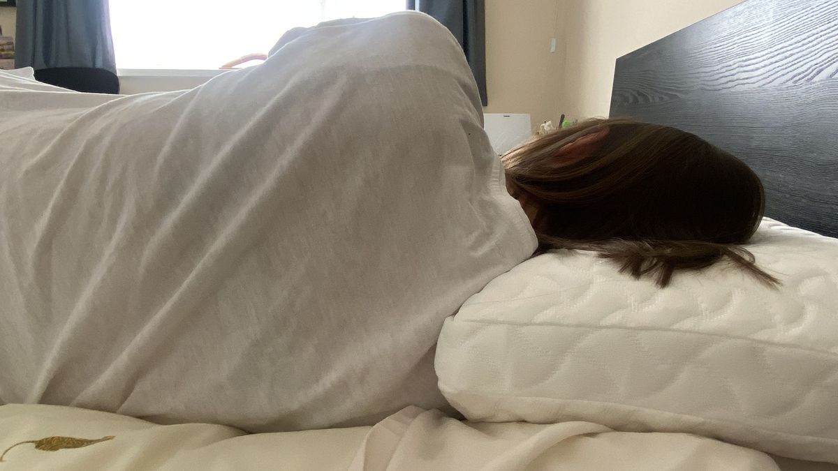 A woman lies on her side with her head resting on the Tempur-Pedic Tempur-Cloud Pillow.