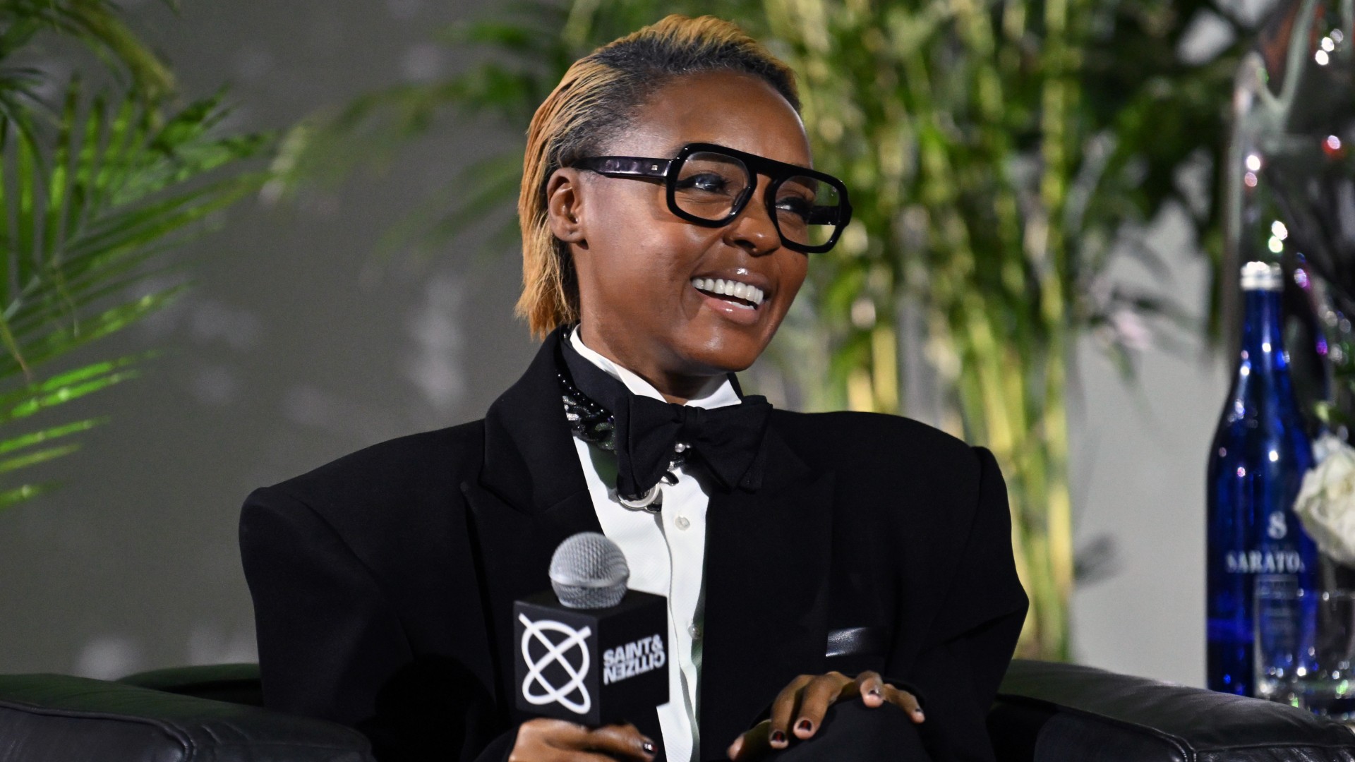 a black woman with short, honey blonde hair being interviewed on an event stage